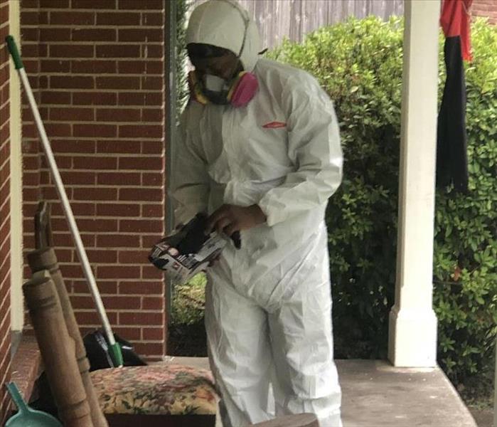 Man wears coveralls and respirator (PPE) to clean mold